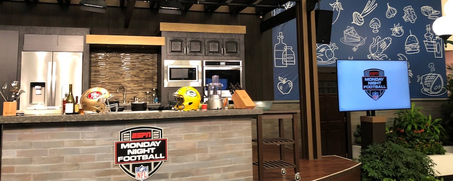 San Francisco 49ers and Greenbay Packers football helmets on a kitchen counter next to a bottle of wine