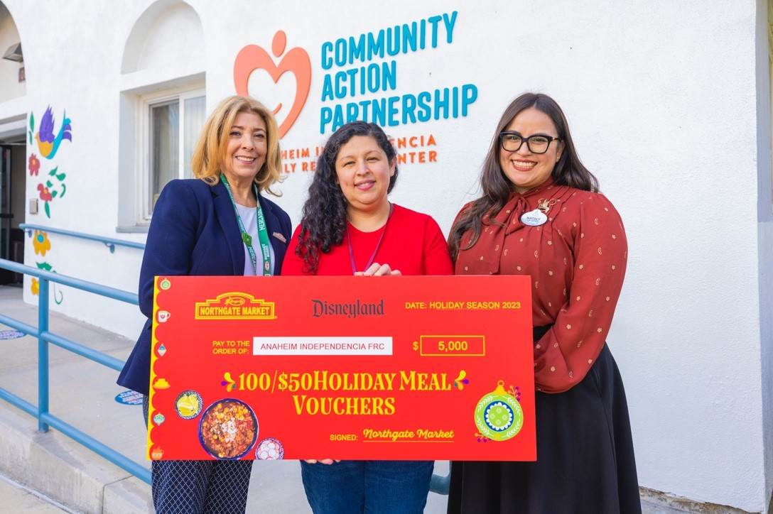 Representatives from Northgate González Market (Teresa Gonzalez), Community Action Partnership Orange County (Carina Guzman Merlan) and Disneyland Resort (2022-2023 Disney Ambassador Nataly Guzman Garcia) present the grocery vouchers during the Dec. 7 community event.